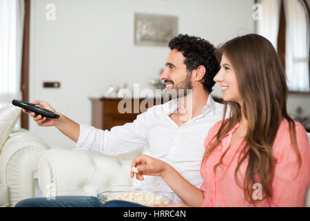 Couple using a remote control while sitting on the couch
