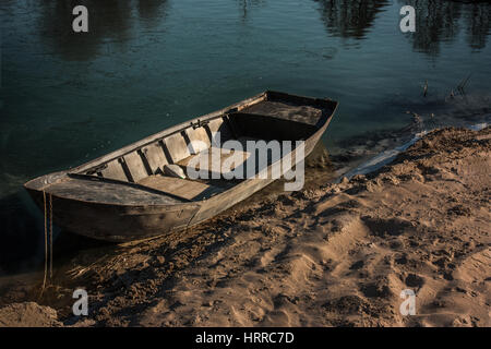Small wooden boat abandoned on the banks of a river in Italy Stock Photo