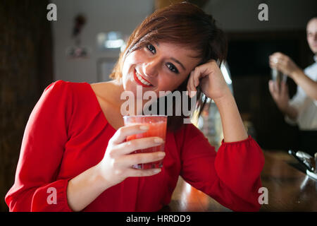 Smiling beautiful young woman holding a cocktail glass Stock Photo