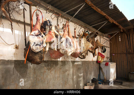 Butchered pig legs hanging on a hook and dried against a wall in china. Stock Photo