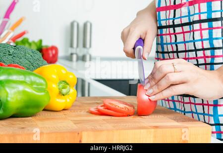 Woman chef cutting peppers. Food preparation in modern kitchen Stock Photo