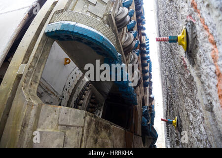 Cutting part with metal blades of a big modern industrial subway drilling machine in front of the wall from where begins the digging. Stock Photo