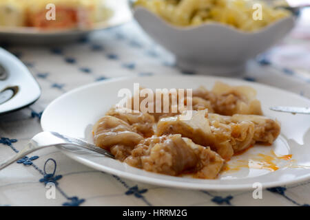 Serbian specialty sarma in the white plate chopped, with other dishes visible in the background Stock Photo
