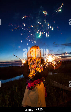 A woman holding sparklers at dusk celebrating the 4th of July at Birch Bay, Washington, USA. Stock Photo