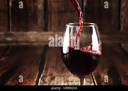 Closeup of glass with red wine on wooden background. Close up of pouring wine into transparent glass. Perfect alcoholic background. Macro of red wine  Stock Photo