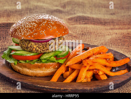 Vegetarian burger with fresh vegetables and sweet potato crisps on wooden plate Stock Photo