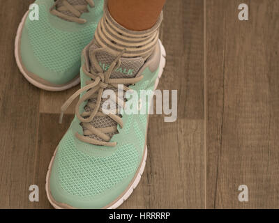 Woman wearing light green sport shoes on wooden floor Stock Photo