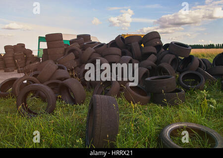 Stack of used tyres lay on green grass background. Pile of used tires Stock Photo