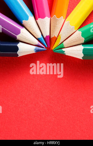 Eight colored pencils in a semicircle on red background macro. Place for the text. Art and design. Painting and drawing. Artist. Stock Photo