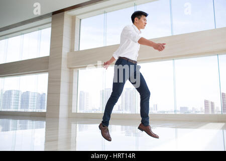 Young businessman jumping in office building Stock Photo