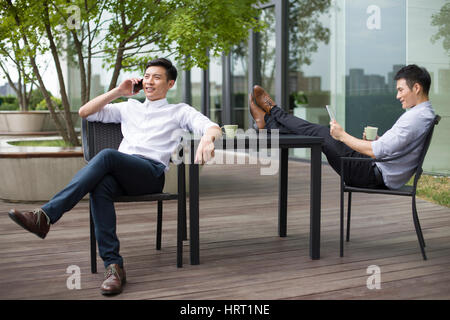 Young businessmen drinking coffee at sidewalk cafe Stock Photo