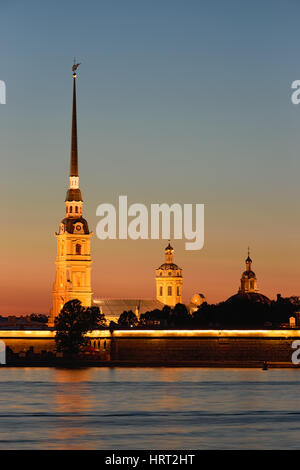 Peter and Paul fortress with the Palace promenade at sunset on a background of pure pink sky with reflection in the water of the Neva river during the Stock Photo