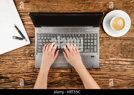 Laptop on a old table with hand of a young woman top view Stock Photo