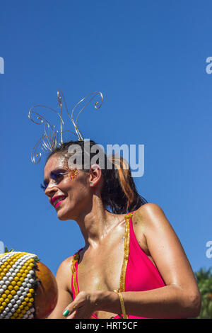 FEBRUARY 9, 2016 - Rio de Janeiro, Brazil - Young brazilian woman in bright costume smiling and playing afoxe during Carnaval 2016 street parade Stock Photo