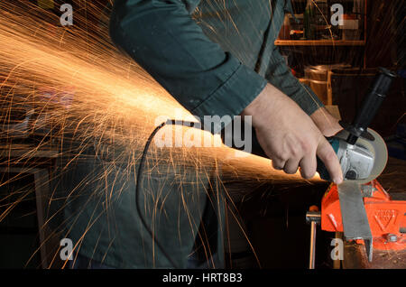 Worker cutting metal with grinder. Sparks while grinding iron Stock Photo