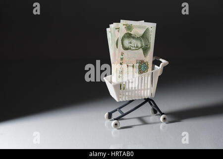 1 Yuan bills / banknotes in shopping cart / trolley against dark background. Metaphor for Chinese economy, budget, spending power, consumer spending. Stock Photo