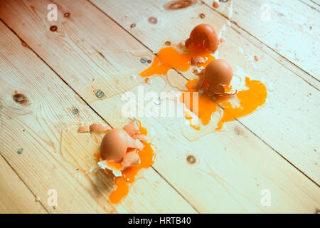 three broken eggs on wooden floor Stock Photo