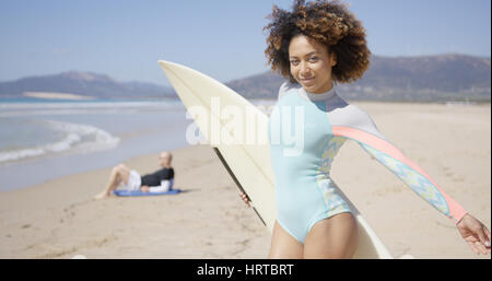 Female wearing lightblue swimsuit posing with surfboard and male lying on beach. Tarifa beach. Provincia Cadiz. Spain. Stock Photo