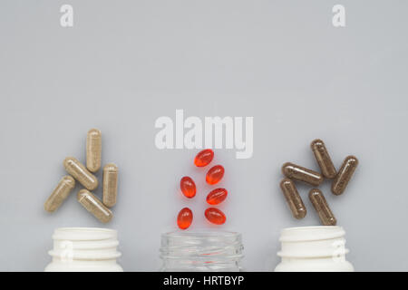 Medicinal capsule spill out of a three plastic bottles on a light surface Stock Photo