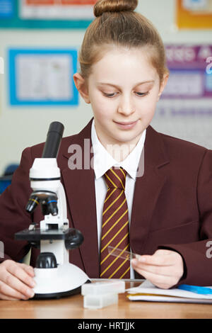 Female Pupil Using Microscope In Science Lesson Stock Photo