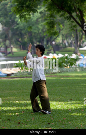 At Lumphini Park, an adult Thai woman practising tai-chi-chuan - a form of Chinese low stress training - in the early morning (Bangkok - Thailand). Stock Photo