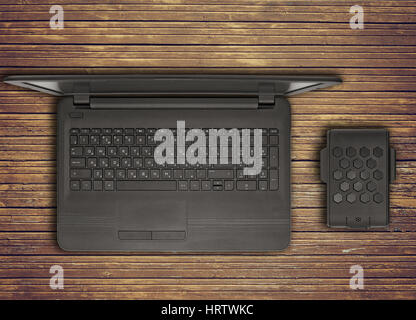 Black laptop with an external hard drive are on the old brown boards. View from above. Stock Photo