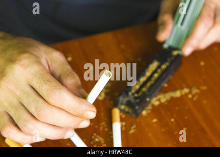 Man rolling cigarettes using fresh tobacco Stock Photo