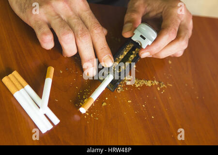 Man rolling cigarettes using fresh tobacco Stock Photo