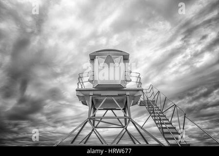 Low angle view of a lifeguard tower against a cloudy sky. Black and white image. Stock Photo