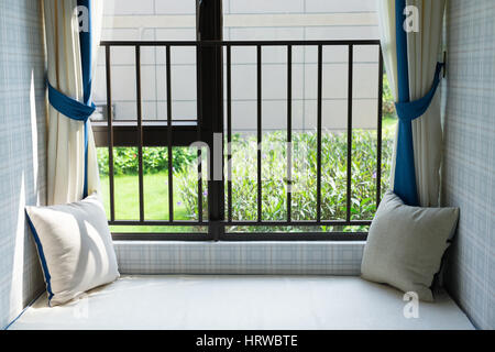 resting area of a cozy window seat with green cushion in the morning horizontal composition Stock Photo