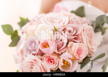 Brides bouquet of roses, tulips and eucalyptus, in her hands Stock Photo