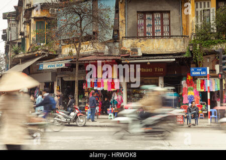 Hanoi, Vietnam - March 4, 2014: Vietnamese man is sitting on the plastic chair near the busy road in Hanoi Old Quarter on March 4, 2014, Vietnam. Stock Photo