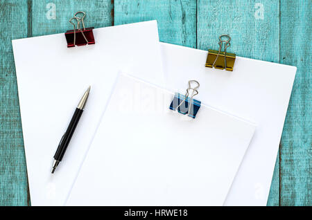 Blue wooden desk table with paper reams and pen. Top view with copy space, flat lay. Stock Photo