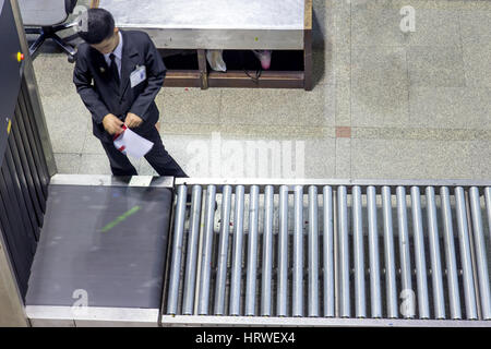 Control baggage at the airport. Security officer at the airport works at scanner for checked luggage of passengers before departure. Stock Photo