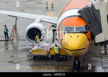 airplane Nok Air parked in the airport Don Muang, Bangkok, Thailand. The plane stands with the tunnel at the airport. Stock Photo