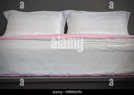 Close up white bedding sheets and pillow on black wooden bed room background, Relaxing concept Stock Photo