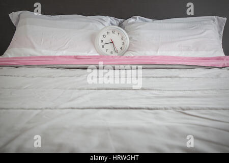 Clock on the bed as wake up in the morning concept. Stock Photo