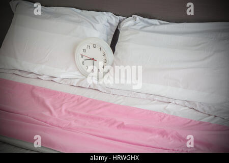 Alarm clock on the bed as wake up in the morning concept. Stock Photo
