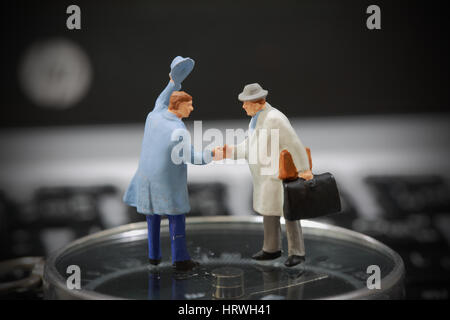 Selective focus of miniature businessman handshake on the compass background as welcome and travel concept. Stock Photo