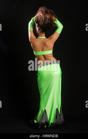 beautiful young brunette in a green suit oriental dance on black background Stock Photo