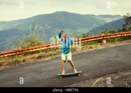 hipster man longboarding extremely action in highway tropics in Asia Stock Photo