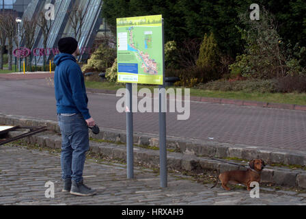 man with dog looking at tourist map of Glasgow Clyde walkway Stock Photo