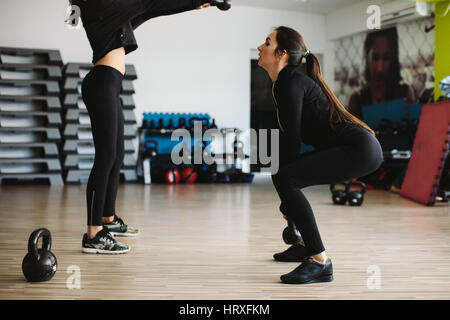 fitness women kettlebell workout in gym. Two women cross fitness workout. Stock Photo