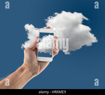 Concept image for cloud computing and online applications showing modern smartphone held in male hand up to sky Stock Photo