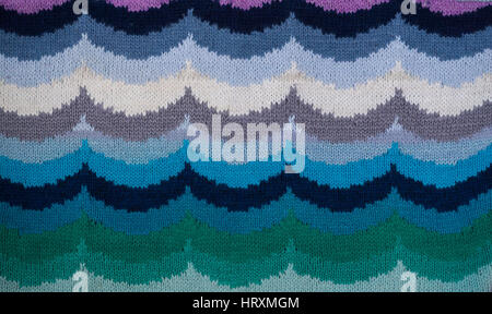 Knitted handmade fabric fragment with an ornament in the form of waves. Background Stock Photo