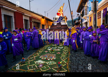 Antigua, Guatemala - April 16, 2014: Man wearing purple robes, carrying a float (anda) during the Easter celebrations, in the Holy Week, in Antigua Stock Photo