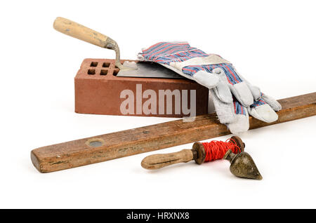 Old construction accessories trowel, bricks, plummet and level on white background. Stock Photo
