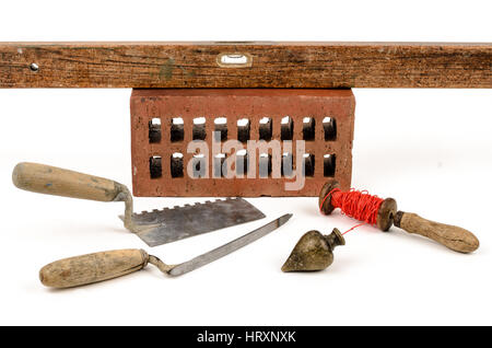 Old construction accessories trowel, bricks, plummet and level on white background. Stock Photo