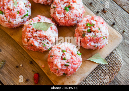 Cooking meatballs with vegetables, rice and spices on wooden cutting board close up