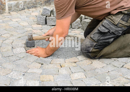 Construction worker installing stone blocks on pavement Stock Photo